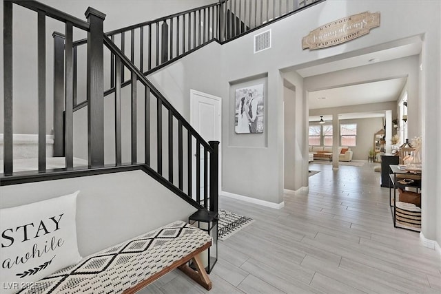 foyer with stairway, wood finished floors, visible vents, and baseboards