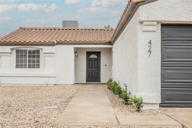 view of exterior entry featuring a tiled roof and stucco siding