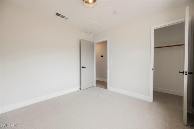 unfurnished bedroom featuring light carpet, attic access, baseboards, visible vents, and a closet