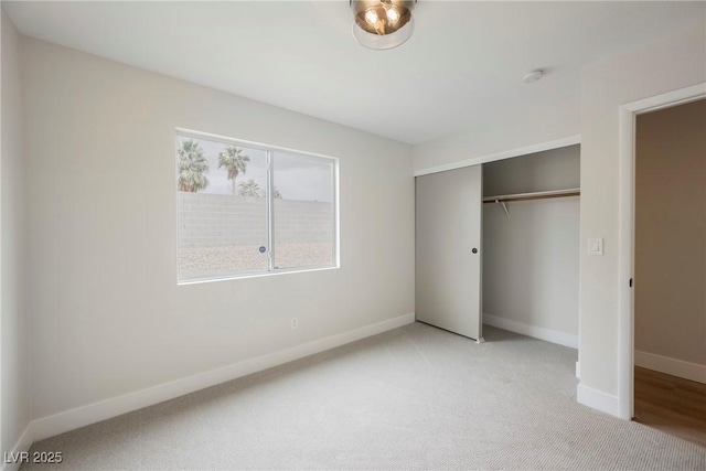 unfurnished bedroom featuring a closet, light colored carpet, and baseboards