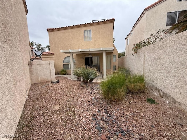 back of house featuring a patio area, a fenced backyard, a tiled roof, and stucco siding