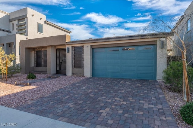 view of front of house featuring an attached garage, decorative driveway, and stucco siding