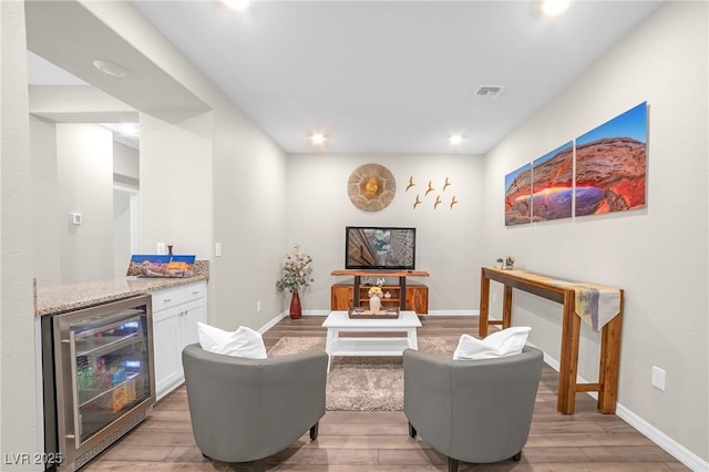 7177 W Camero Ave, Las Vegas, NV 89113 - living room with visible vents, light wood-style floors, a bar, beverage cooler, and baseboards