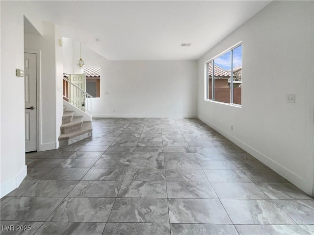 spare room with lofted ceiling, baseboards, stairs, and visible vents