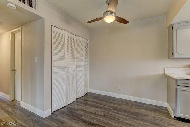 interior space featuring visible vents, baseboards, dark wood finished floors, and a ceiling fan