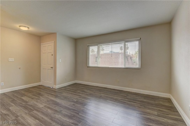 empty room with a textured ceiling, baseboards, and wood finished floors