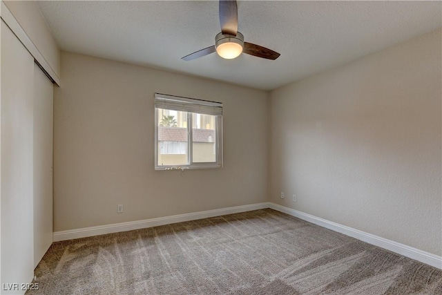 unfurnished room with carpet floors, a textured ceiling, baseboards, and a ceiling fan