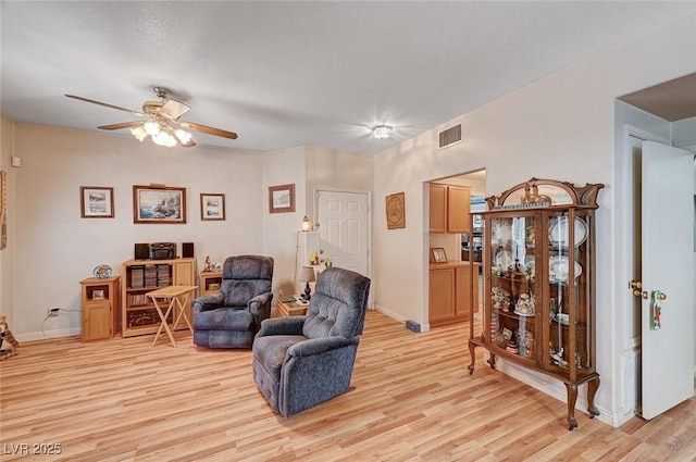 living room with a ceiling fan, baseboards, visible vents, and light wood-type flooring