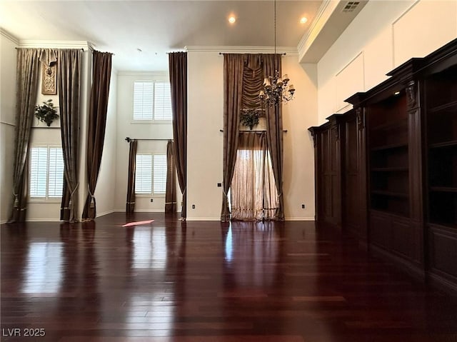 unfurnished room featuring baseboards, wood finished floors, a wealth of natural light, and crown molding