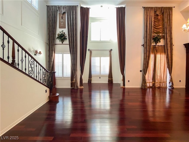 living room with stairway, wood finished floors, a towering ceiling, and baseboards