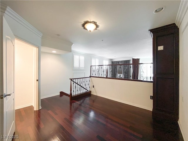 spare room with a wealth of natural light, crown molding, baseboards, and wood finished floors