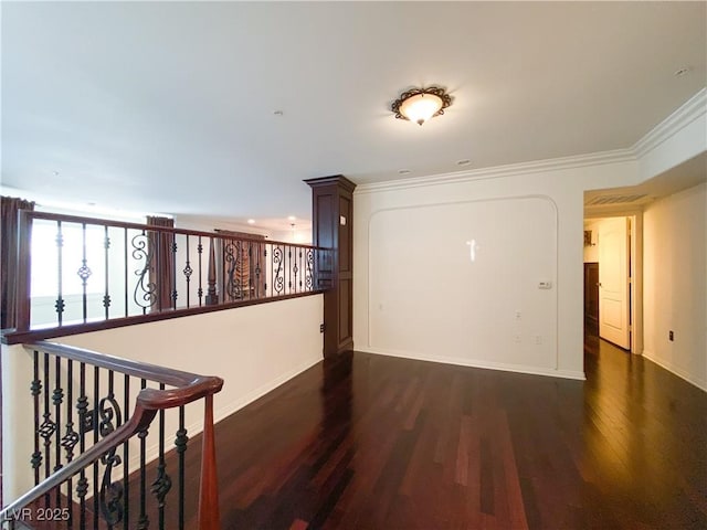 hall featuring baseboards, ornamental molding, wood finished floors, and an upstairs landing