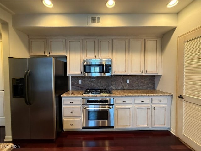 kitchen with stainless steel appliances, tasteful backsplash, visible vents, and light stone counters