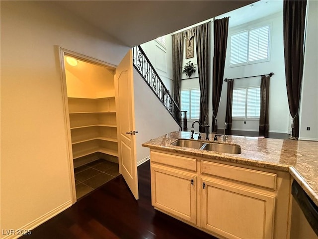 bar with dark wood-style flooring, a sink, baseboards, stairway, and dishwasher