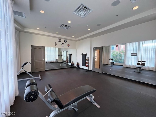 workout area with visible vents, a raised ceiling, and recessed lighting