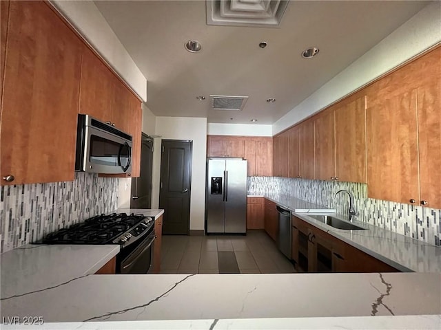 kitchen with light tile patterned floors, a sink, visible vents, appliances with stainless steel finishes, and brown cabinets