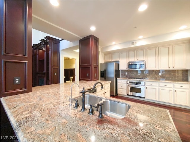 kitchen with stainless steel appliances, tasteful backsplash, a sink, and visible vents