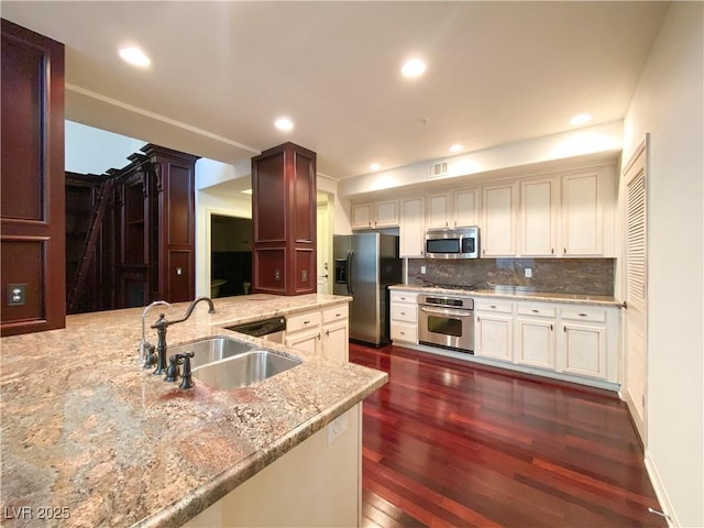 kitchen with visible vents, dark wood finished floors, appliances with stainless steel finishes, a sink, and backsplash