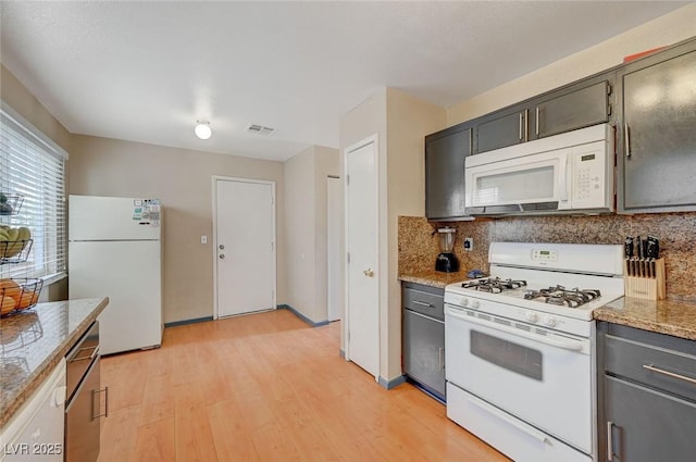 kitchen with white appliances, visible vents, light wood-type flooring, decorative backsplash, and light stone countertops