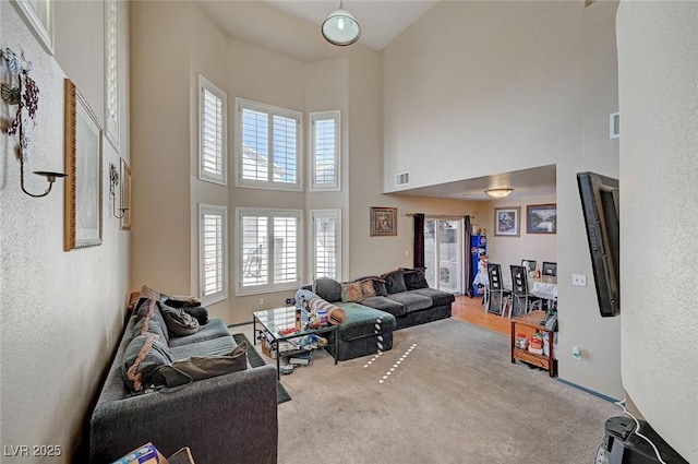 carpeted living room featuring a high ceiling and visible vents