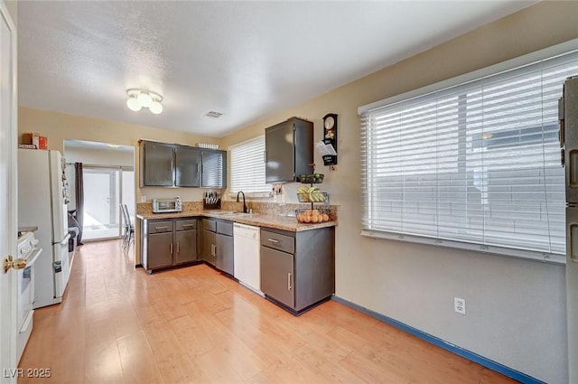 kitchen featuring white appliances, baseboards, light wood-style flooring, light countertops, and a sink