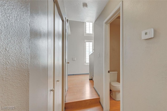 hall featuring light wood finished floors and a textured ceiling