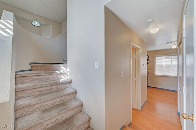 stairway featuring visible vents and wood finished floors