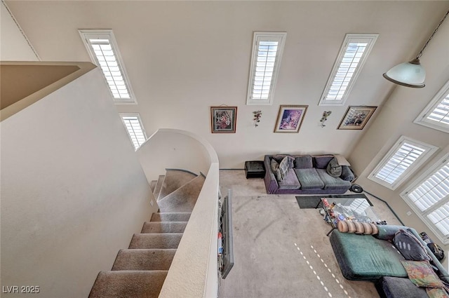 living area featuring carpet floors, a wealth of natural light, a high ceiling, and stairs