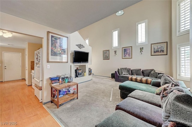 living area featuring light wood-type flooring and a high ceiling