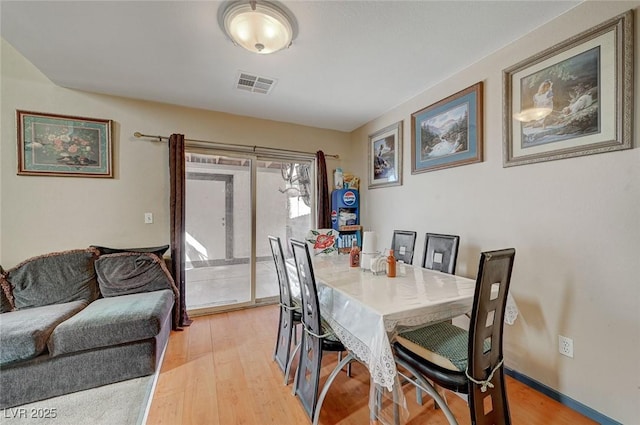 dining area featuring light wood-style flooring, visible vents, and baseboards