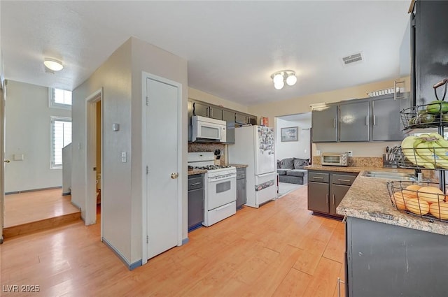 kitchen with white appliances, a toaster, visible vents, light countertops, and light wood-type flooring