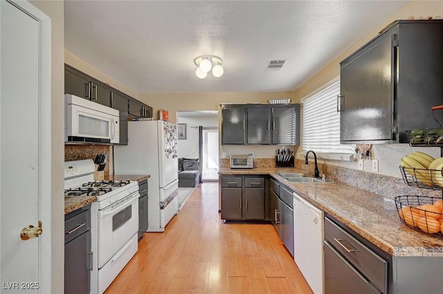 kitchen with light wood-style flooring, a toaster, white appliances, a sink, and visible vents