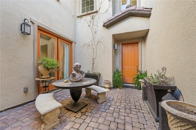 view of exterior entry with stucco siding, a tile roof, and a patio