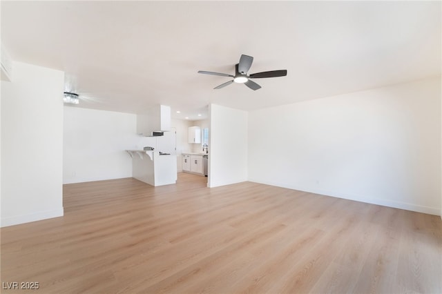 unfurnished living room with baseboards, ceiling fan, and light wood finished floors