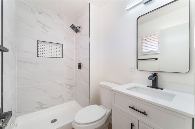 full bath with a tile shower, vanity, and toilet