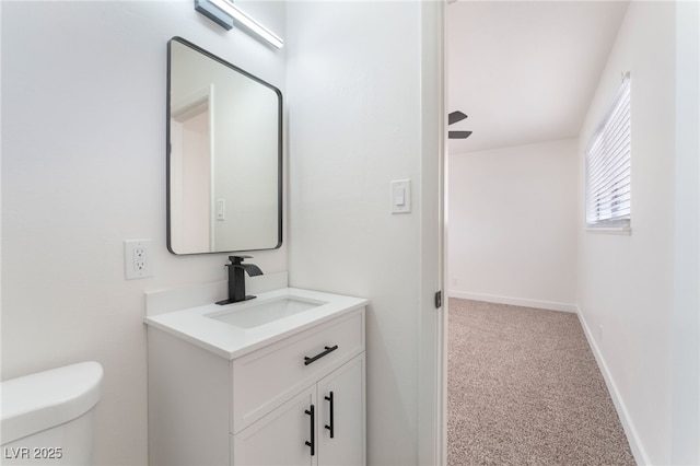 half bath featuring toilet, vanity, and baseboards