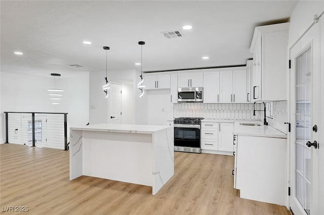 kitchen with visible vents, appliances with stainless steel finishes, light wood-style flooring, and a sink