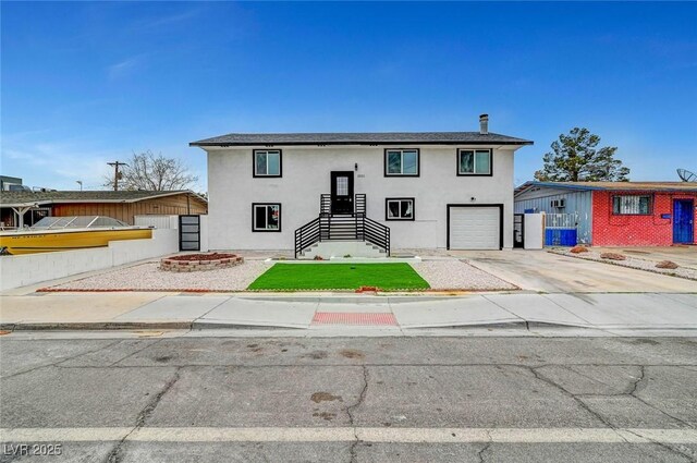 bi-level home with a garage, driveway, fence, and stucco siding