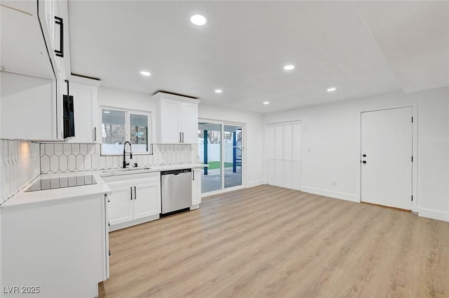 kitchen featuring black electric stovetop, a sink, light countertops, stainless steel dishwasher, and backsplash