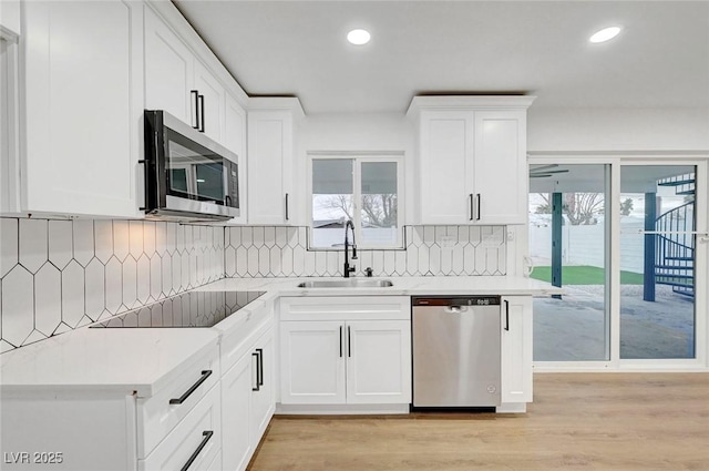 kitchen featuring a sink, light countertops, appliances with stainless steel finishes, decorative backsplash, and light wood finished floors