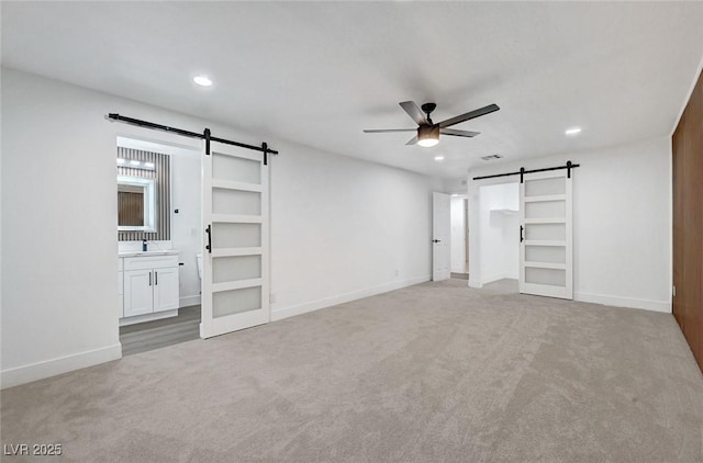 unfurnished bedroom featuring a barn door, carpet flooring, and recessed lighting