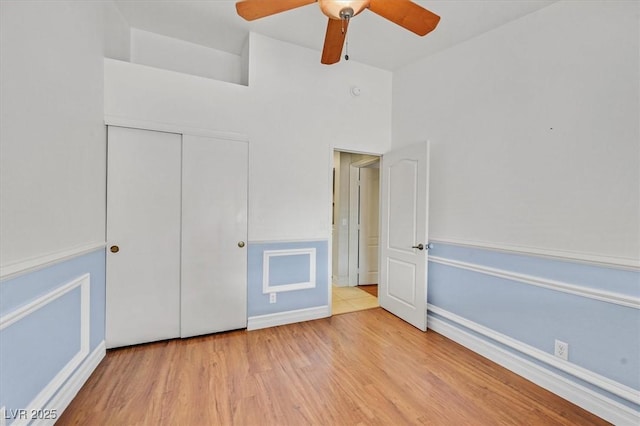 unfurnished bedroom featuring a ceiling fan, a closet, and wood finished floors