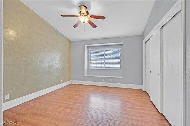 unfurnished bedroom with light wood-type flooring, ceiling fan, baseboards, and a closet