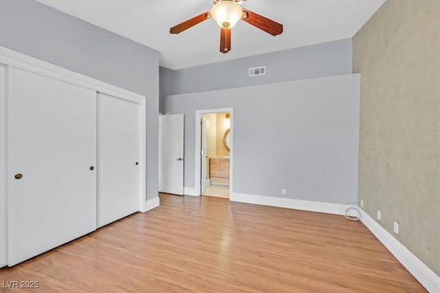 unfurnished bedroom with baseboards, visible vents, light wood-style flooring, ensuite bathroom, and a closet