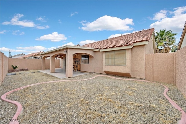 rear view of property featuring stucco siding, a fenced backyard, a tiled roof, and a patio