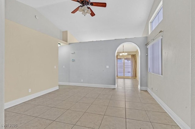 empty room with light tile patterned floors, baseboards, arched walkways, high vaulted ceiling, and ceiling fan with notable chandelier