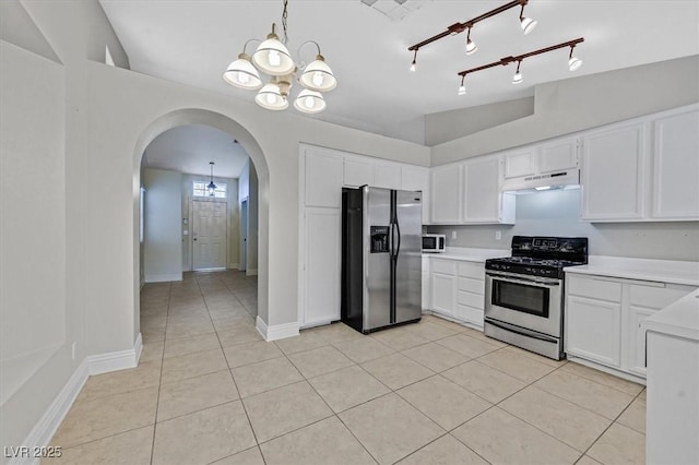 kitchen featuring arched walkways, an inviting chandelier, stainless steel appliances, light countertops, and under cabinet range hood