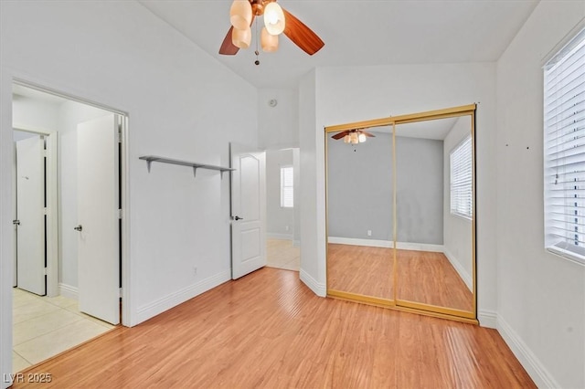 unfurnished bedroom with ceiling fan, lofted ceiling, baseboards, a closet, and light wood-type flooring