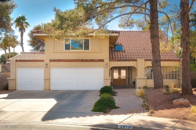 mediterranean / spanish house featuring driveway, stucco siding, french doors, and a tiled roof