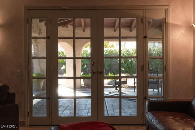 doorway to outside with plenty of natural light, french doors, and a textured wall